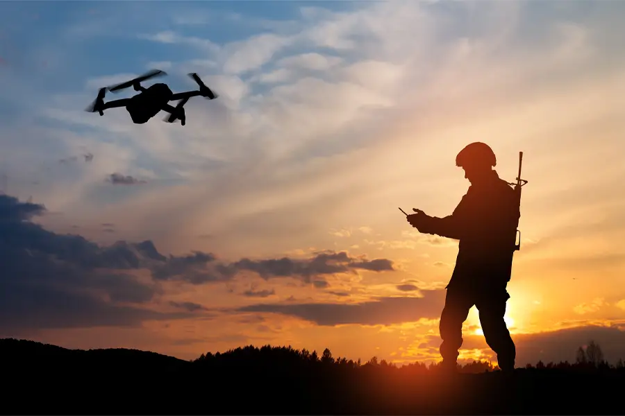 soldier flying drone at sunset